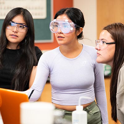 Three students work together in chemistry lab.
