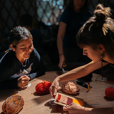 Two people participate in a traditional weaving workshop.