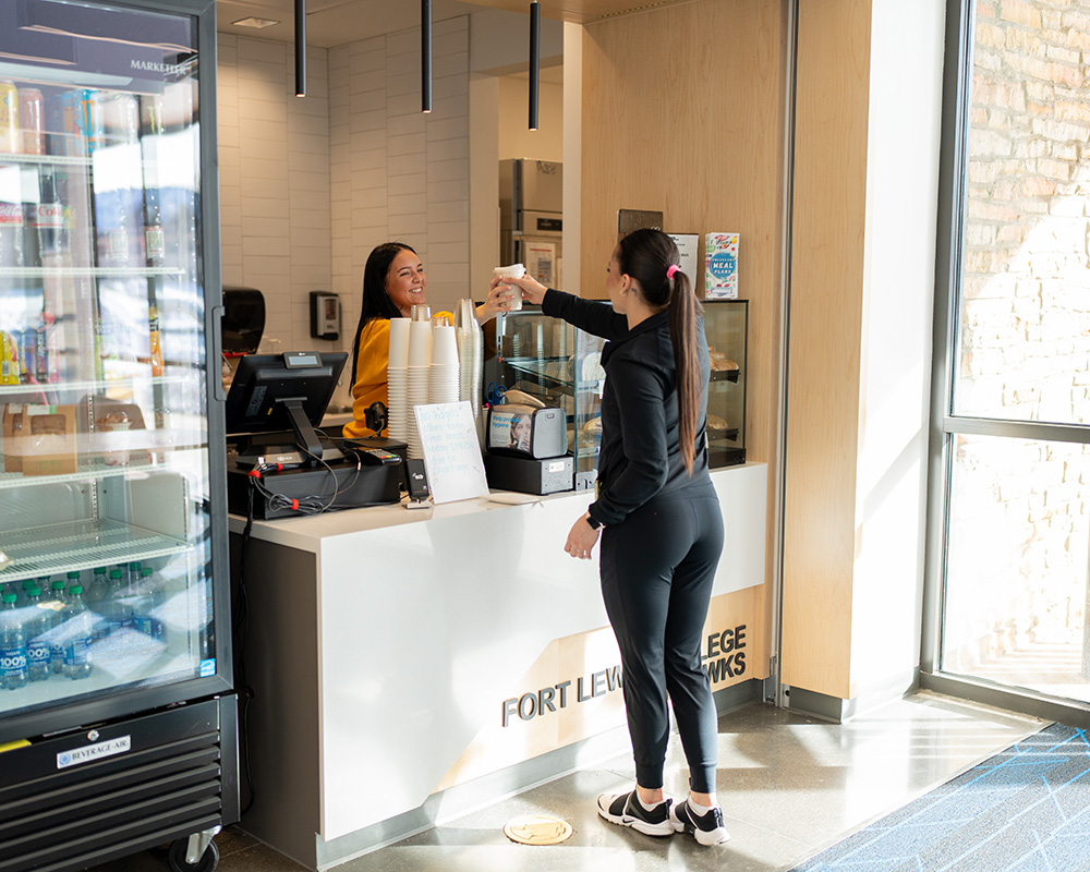 A student worker serving another student coffee at Summit Sips in Schlessman Family Hall